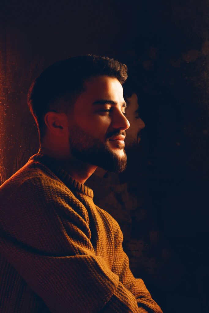 Side view portrait of a bearded man in a warm knitted sweater, softly smiling.