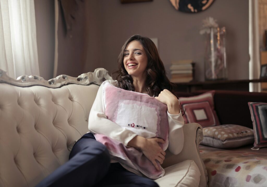 Woman enjoying a relaxed moment on a stylish sofa, exuding warmth and happiness in a cozy living room.